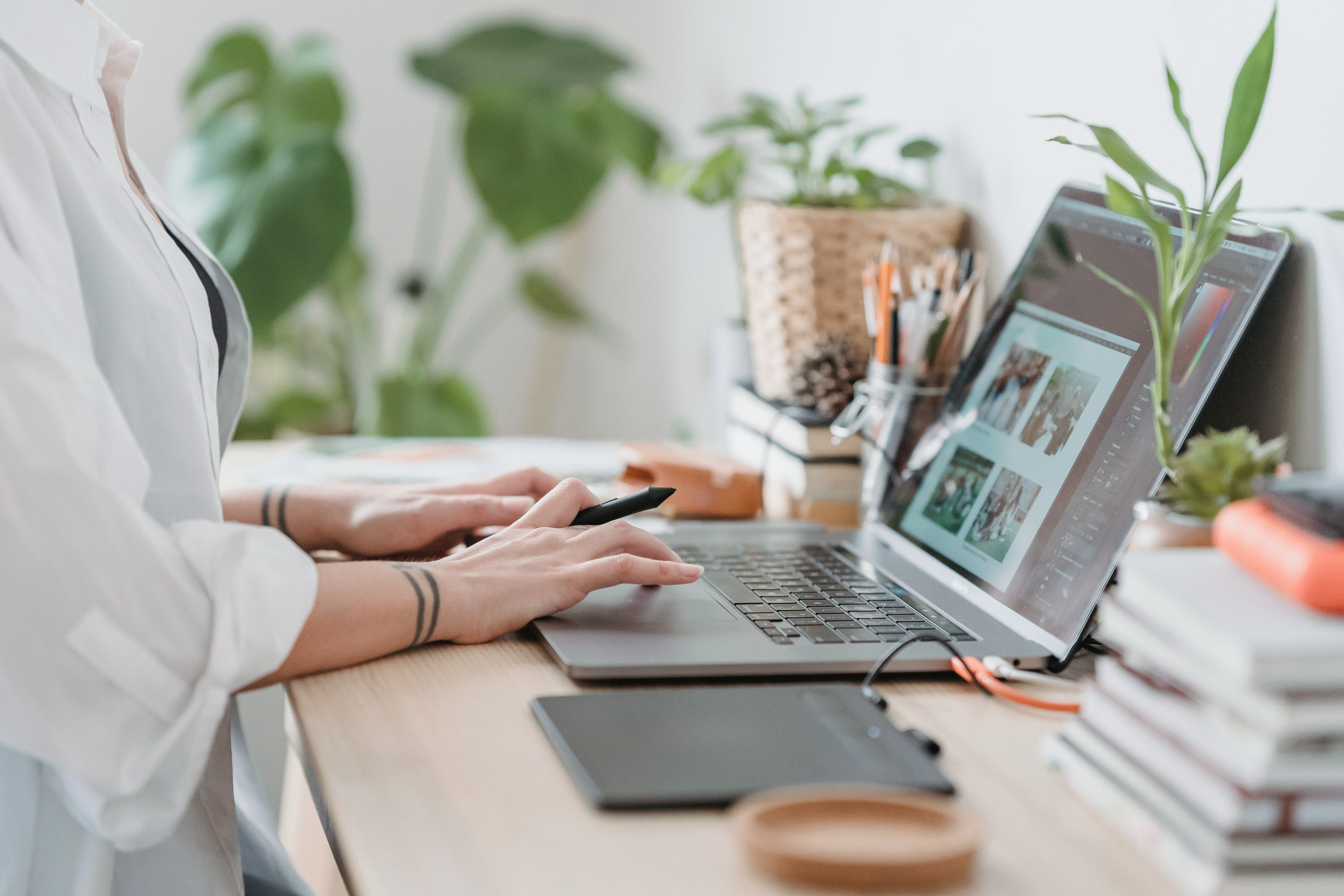 A product designer exploring visual ideas on a laptop beside a sketching tablet.