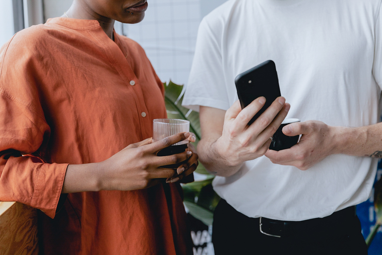 Two colleagues sharing a moment over a phone, with coffee in hand.
